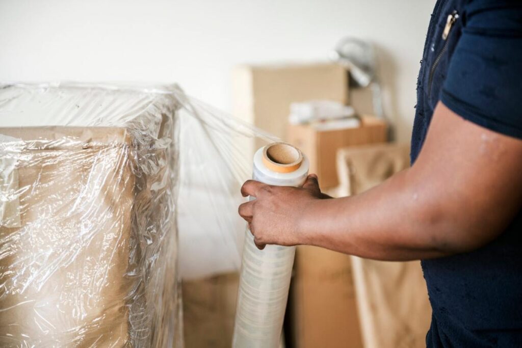 man wrapping furniture for moving box